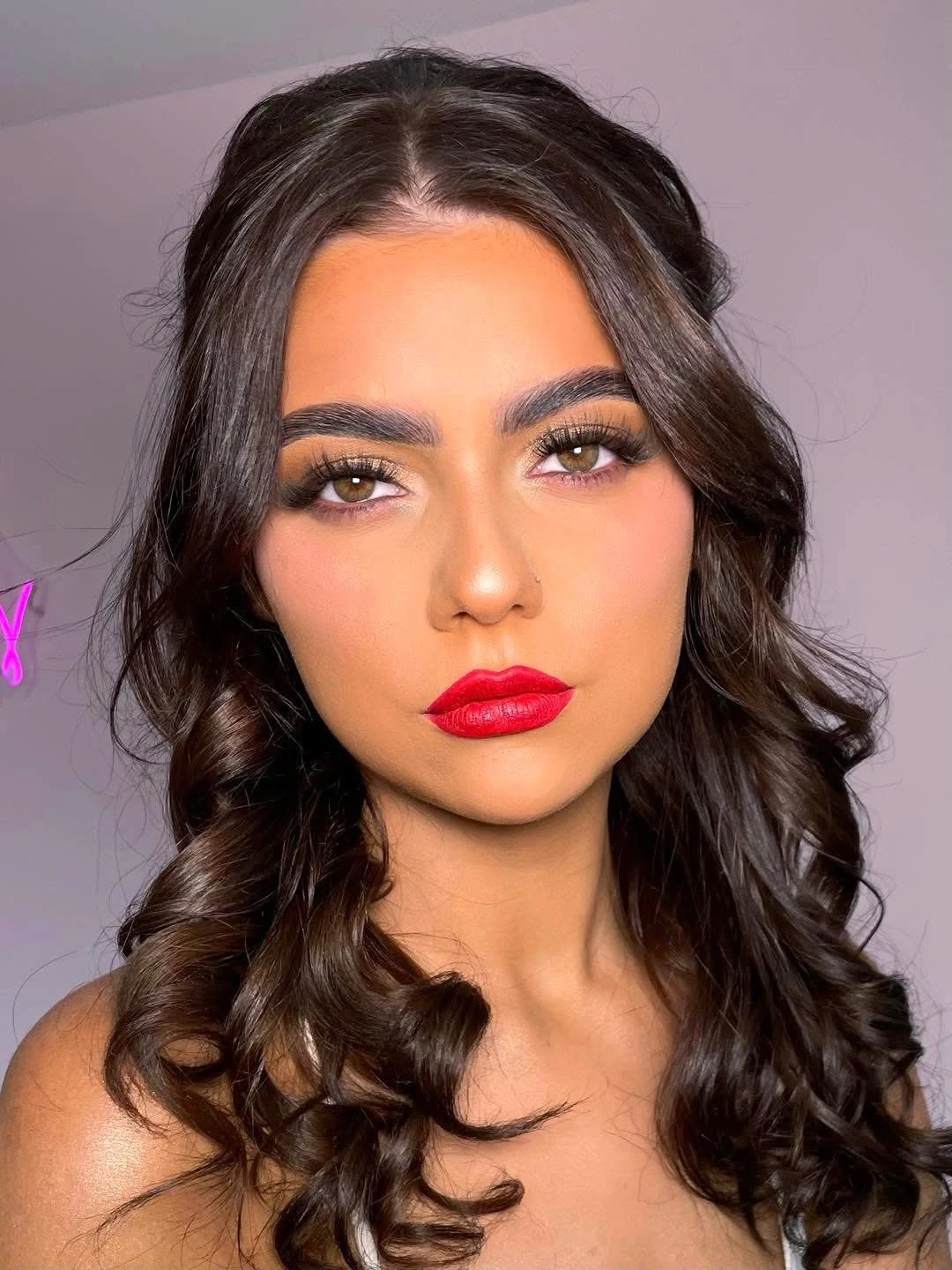 Defined eyes and bright red lipstick on a dark-haired client