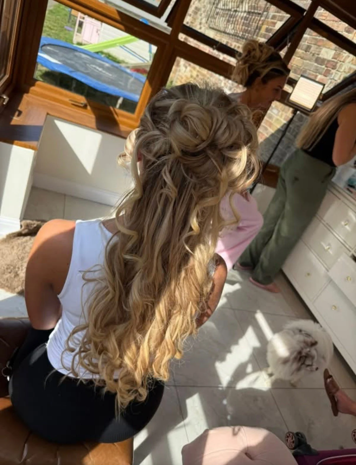 A blonde half-up hairstyle with pinned curls and flowing curled lengths