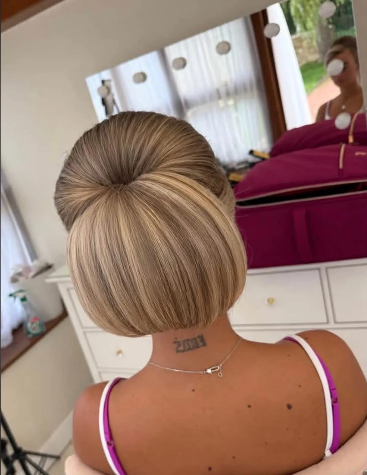 A smooth, sculpted blonde chignon showing Amber’s polished pinning and finishing technique